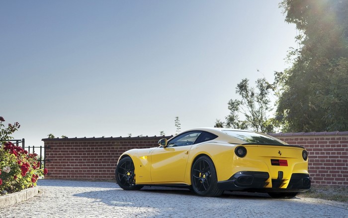 Yellow Ferrari F12berlinetta Novitec Rosso parked on cobblestone