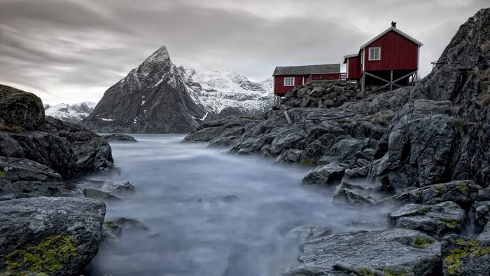 Red houses on rocky coast with snowy mountains in Norway