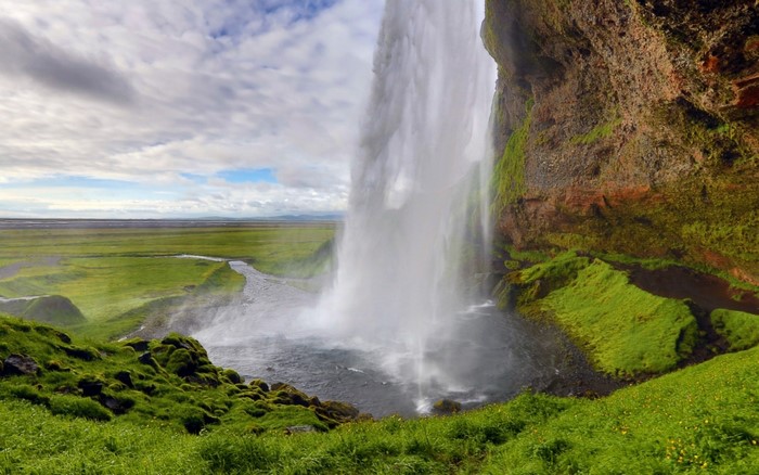 Waterfall cascading over mossy rocks in Iceland landscape
