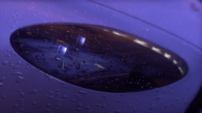 Close-up of a car headlight with raindrops