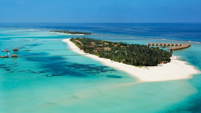 Aerial view of a tropical island resort with overwater bungalows