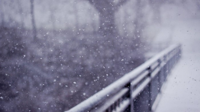 Snow falling on a railing during winter
