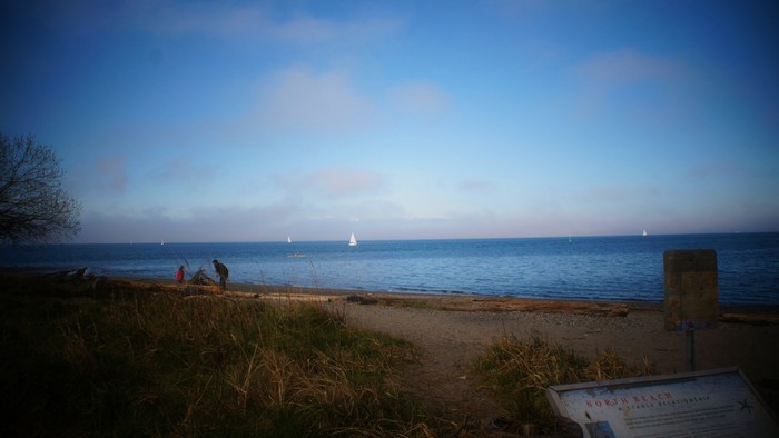 People on North Beach with sailboats on the water