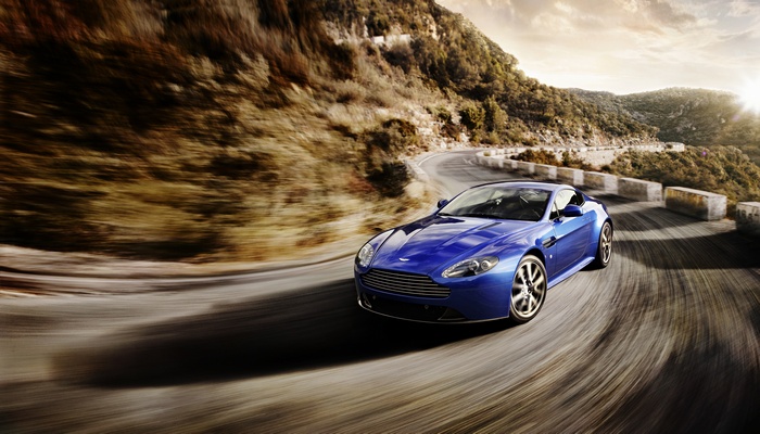 Blue Aston Martin Vantage driving on a mountain road