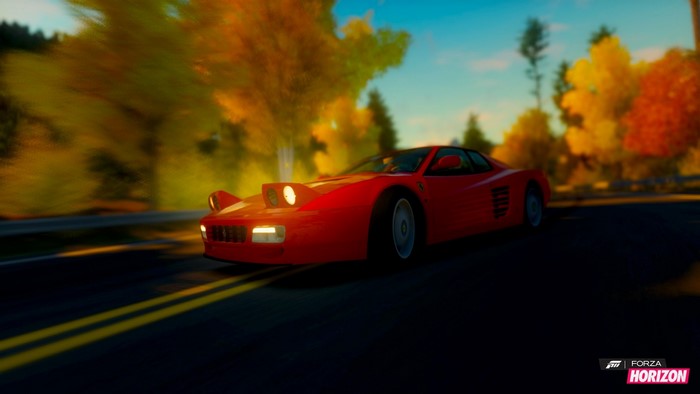 Red Ferrari Testarossa driving on a road during autumn