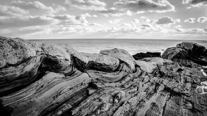Monochrome landscape of rocky coast and ocean under clouds