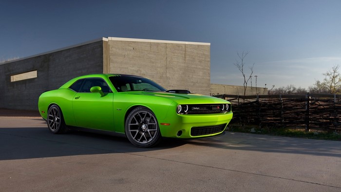 Green Dodge Challenger parked near a concrete wall