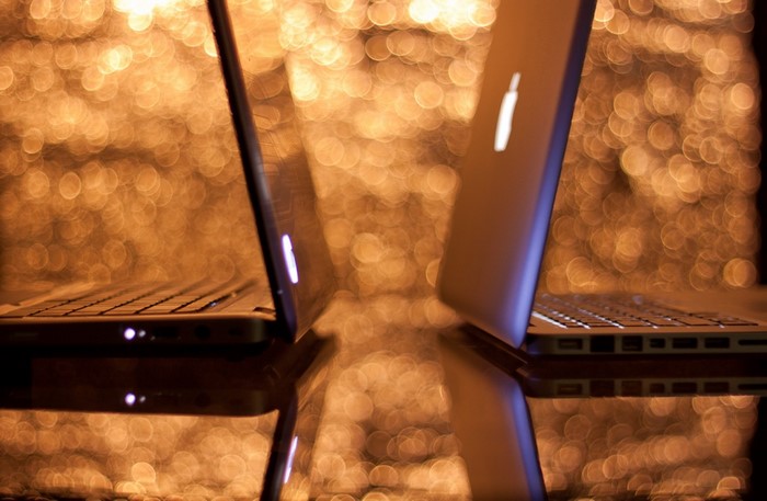 Two MacBooks facing each other with bokeh background