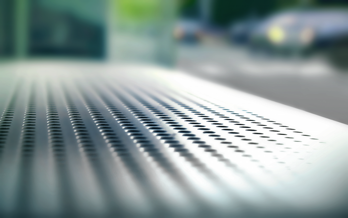 Close-up of perforated metal surface with blurred background