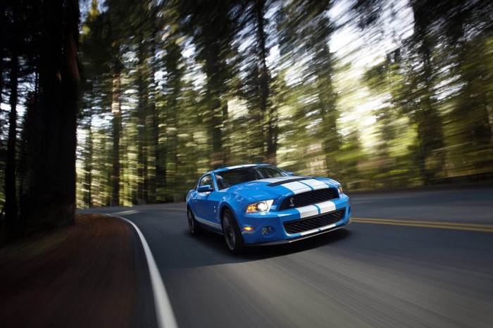 Blue Ford Mustang Shelby GT500 driving on a forest road