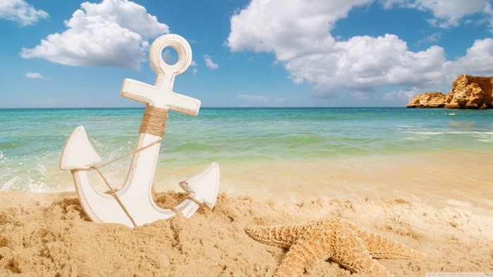 Anchor and starfish on a sandy beach with ocean waves