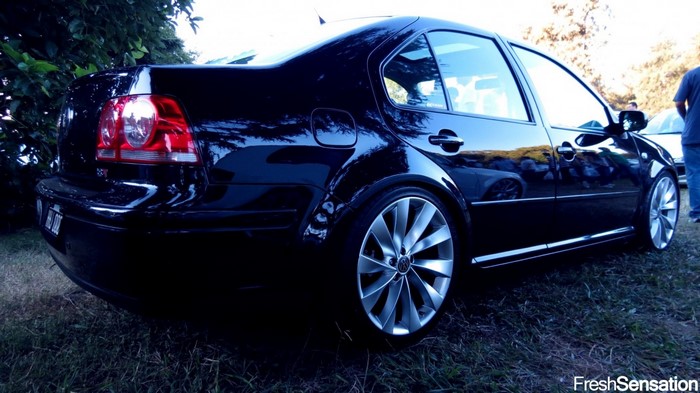 Black Volkswagen Jetta with custom rims parked on grass