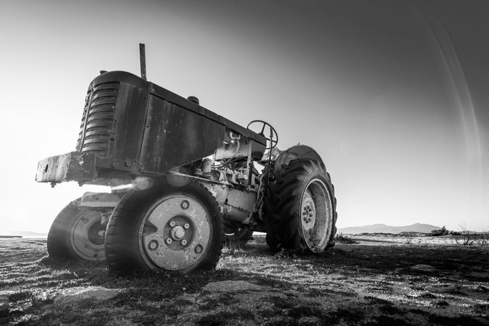 Monochrome image of an old tractor on a field