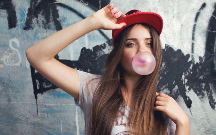 Girl in red cap blowing bubble gum