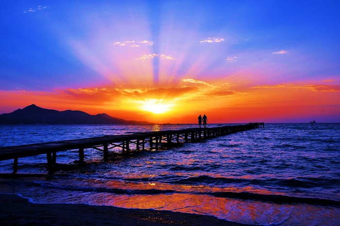 Couple walking on a pier at sunset over the sea