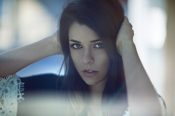 Woman with dark hair and freckles looking at viewer