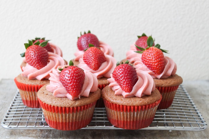 Strawberry cupcakes with pink frosting on a cooling rack