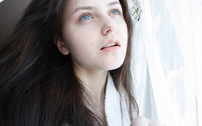 Woman with long dark hair and blue eyes looking up