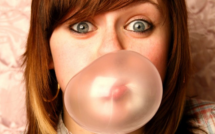 Girl blowing pink bubble gum close up