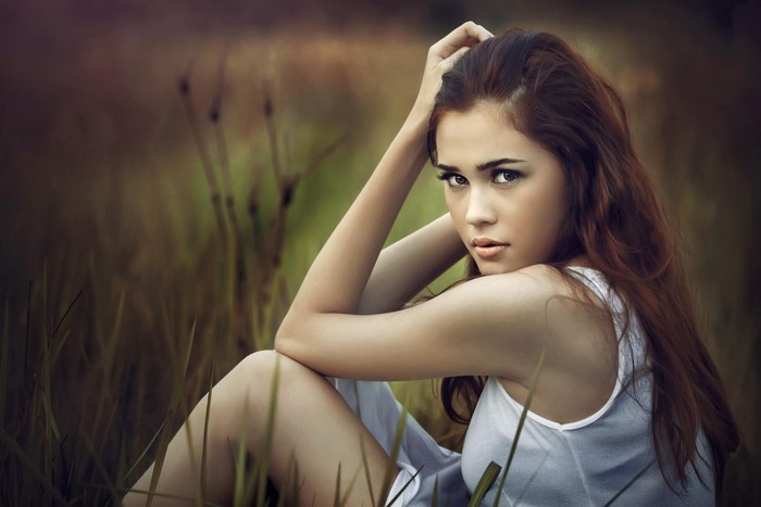 Woman with long brown hair sitting in grass