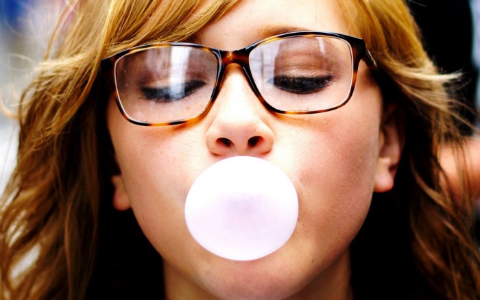 Girl with glasses blowing bubble gum