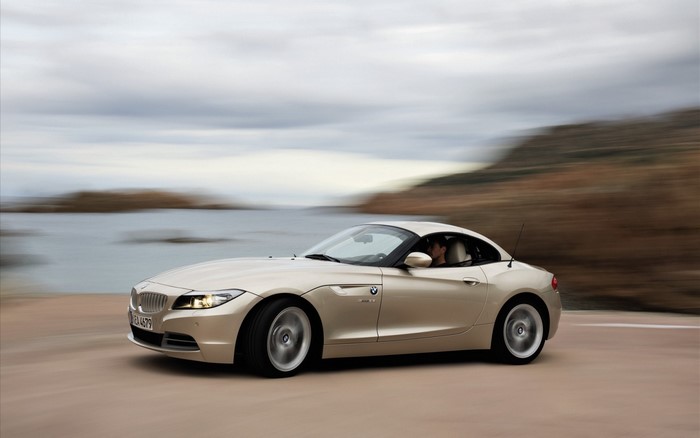 Gold BMW Z4 Coupe driving on a coastal road