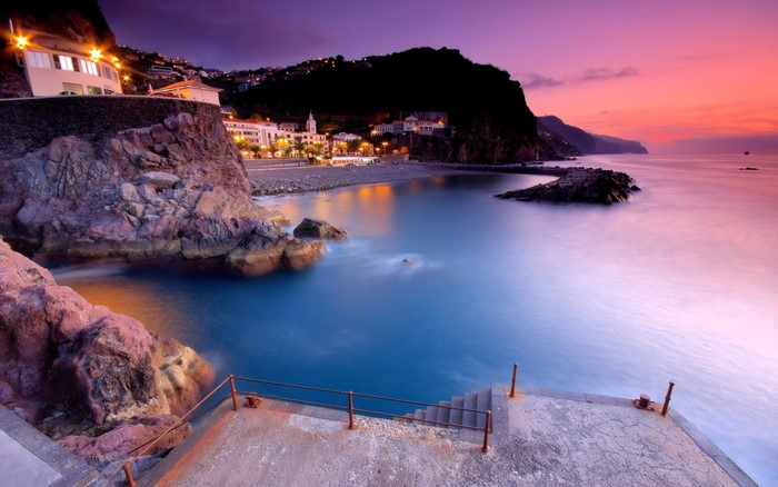 Coastal town at dusk with ocean and rocky shore