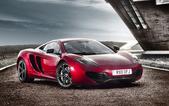 Red McLaren MP4-12C sports car on a gravel road