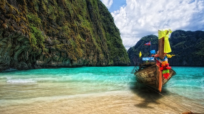 Longtail boat on a tropical beach with limestone cliffs
