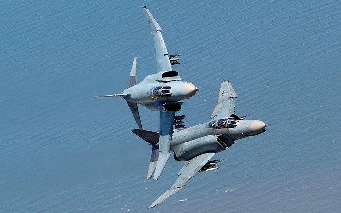Two F-4 Phantom II fighter jets performing aerobatics