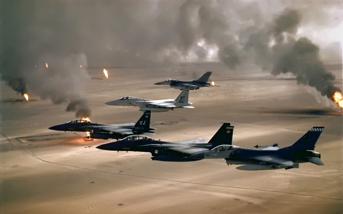 F-15 Eagle and F-16 Fighting Falcon aircraft fly over burning oil fields