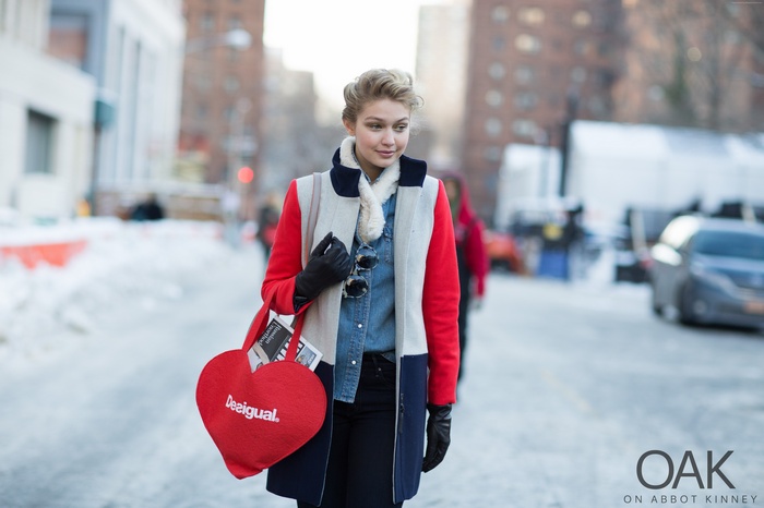 Gigi Hadid wearing a color-block coat and carrying a heart bag