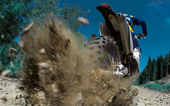 Motorcycle rider kicking up dirt on a trail