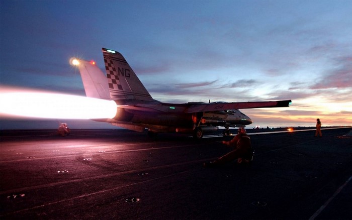 Grumman F-14 Tomcat launching from aircraft carrier at sunset