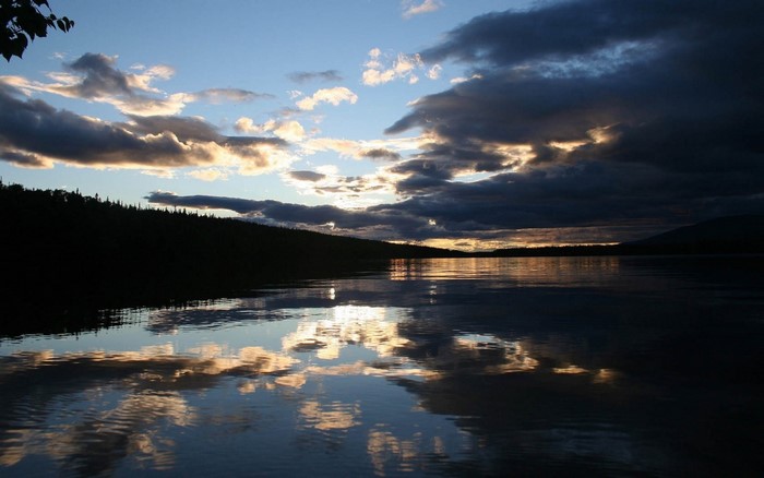 Sunset over a calm lake with dramatic clouds