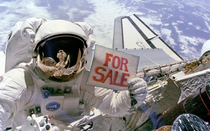 Astronaut holding a "FOR SALE" sign in space