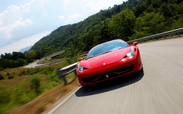 Red Ferrari 458 Italia driving on a winding mountain road