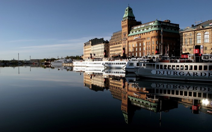 Boats docked in a city harbor with reflections