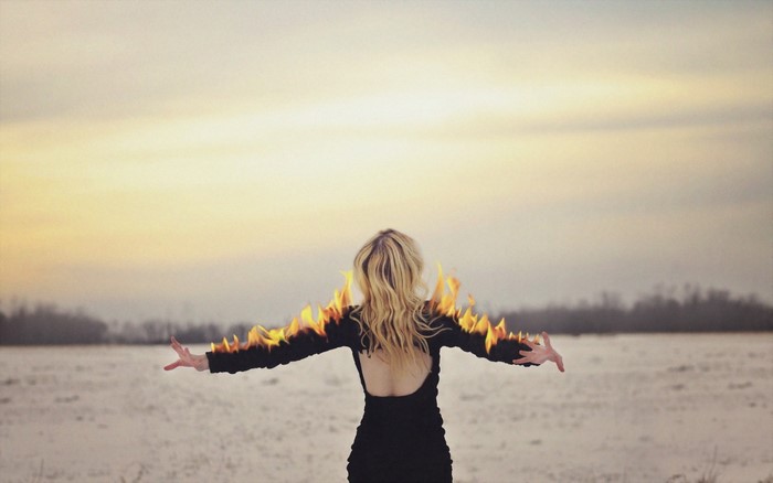 Woman with fire on arms at sunset