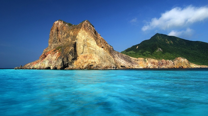 Rocky island with green hills and turquoise water