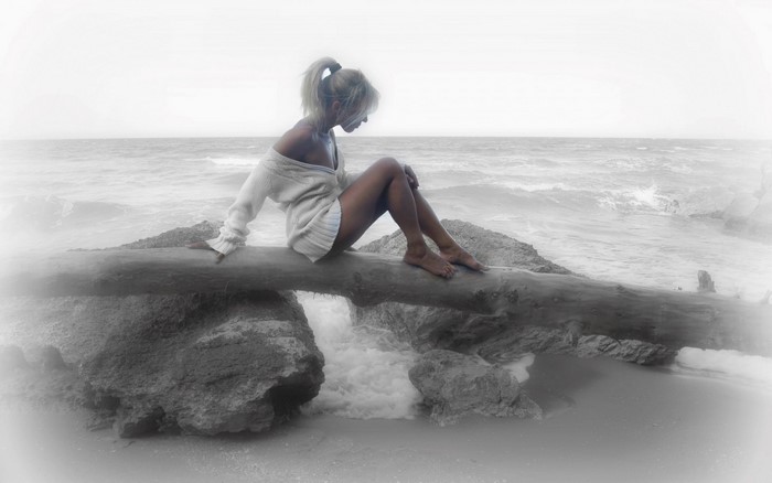 Woman sitting on a log by the sea