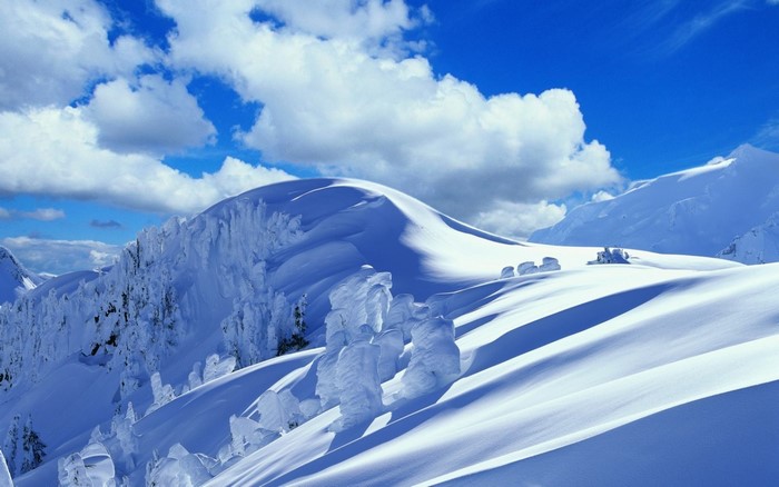 Snowy mountains under a blue sky with clouds