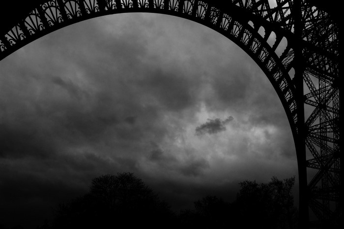 Eiffel Tower arch against stormy sky