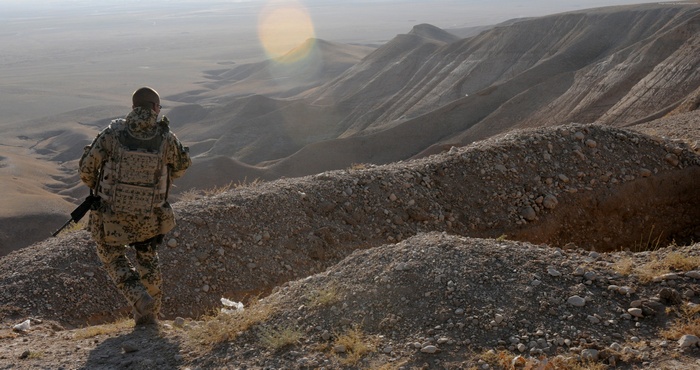 Soldier with weapon in mountainous desert landscape