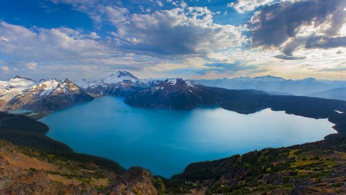 Turquoise lake surrounded by snow-capped mountains and forests