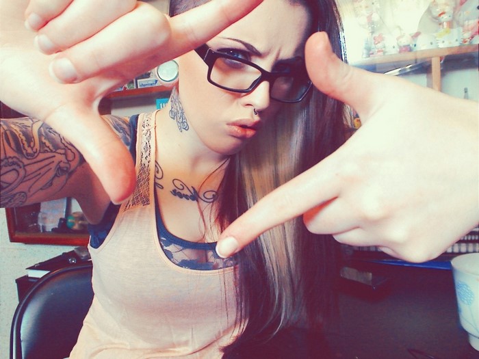 Woman with glasses and tattoos framing her face