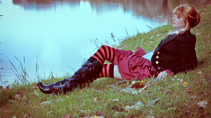 Redhead woman in costume lying by a lake