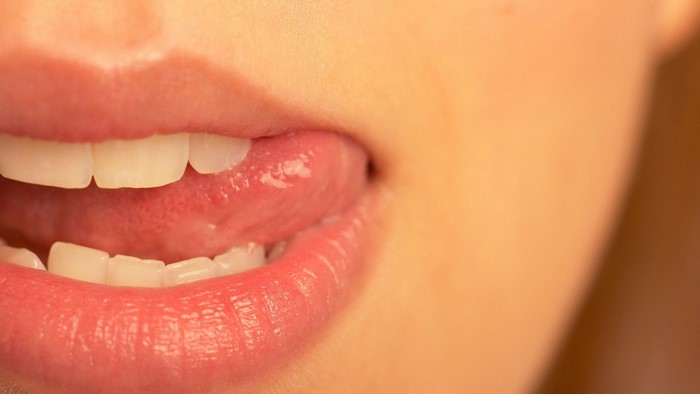 Close-up of a woman's mouth with tongue licking lips