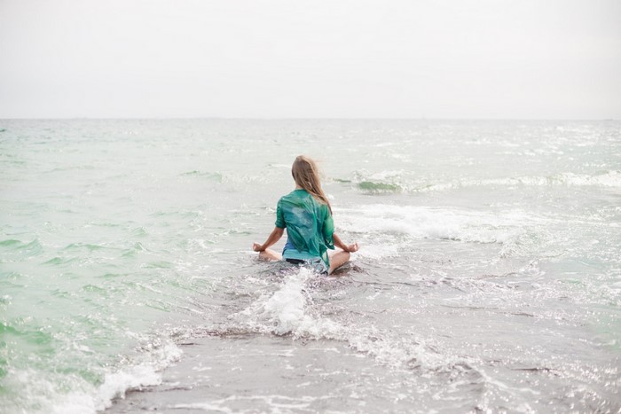 Woman meditating on the shore of the sea