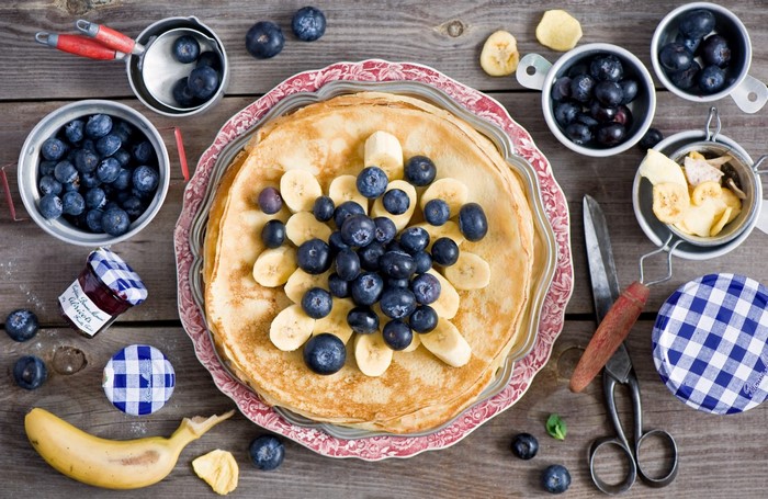 Pancakes with blueberries and bananas on a wooden table